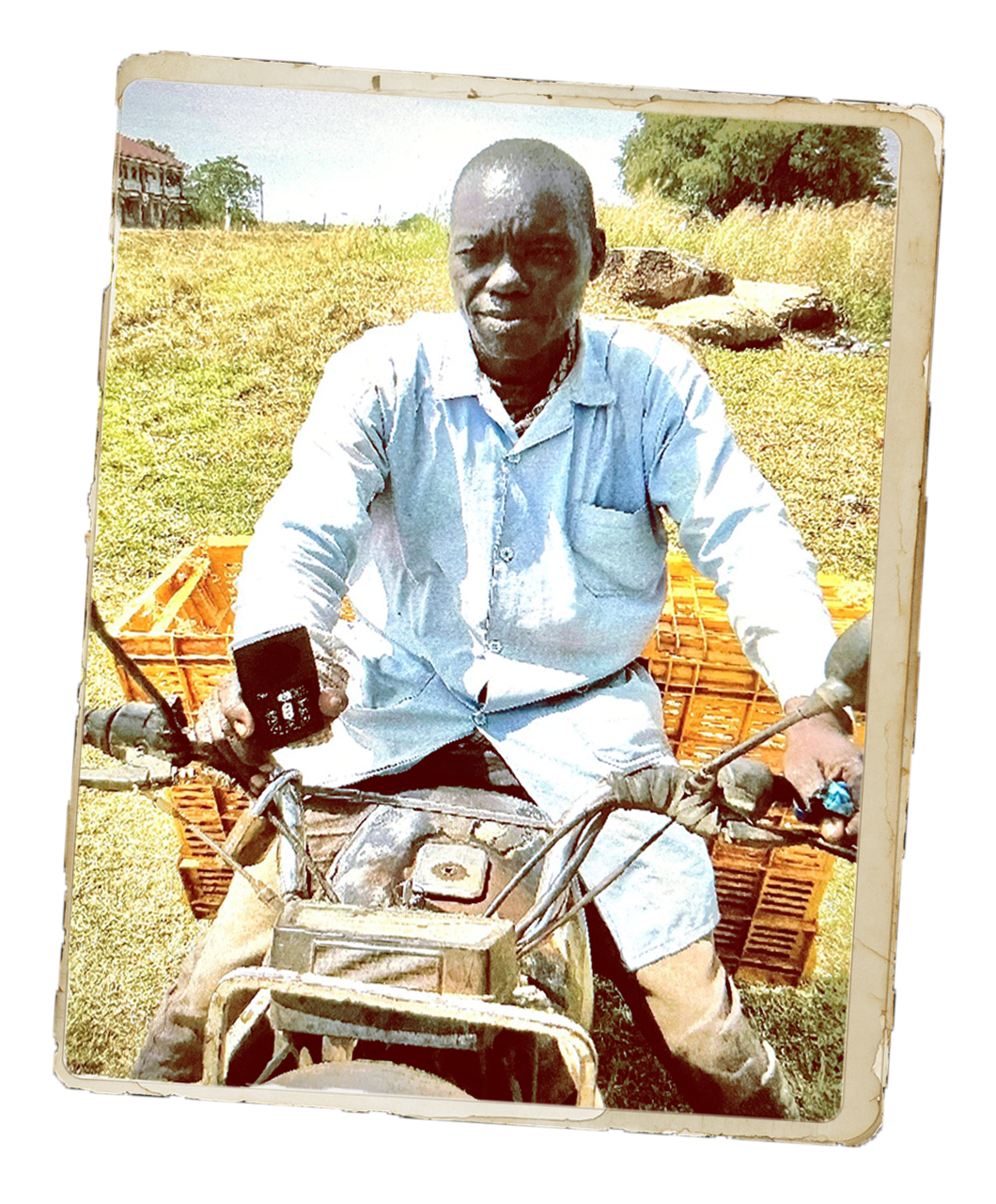 Amari, an egg seller, sits on a motorbike outdoors beside stacked crates, holding a small audio device, representing how he shares Scripture through an Audio Bible as he travels between villages.